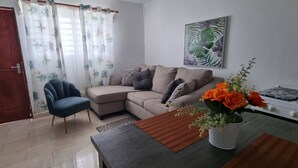 A living room with a sofa, a blue armchair, a coffee table, and a vase with flowers. - Aventura Residences  (Lowlands)