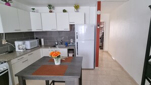 A compact kitchen with white cabinets, a microwave, a refrigerator, and a coffee maker. - Aventura Residences  (Lowlands)