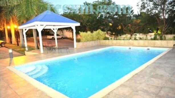 A rectangular swimming pool with a white and blue structure nearby. - Aventura Residences  (Lowlands)