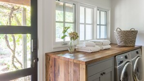 Un espace buanderie avec un plan de travail en bois, un lave-linge et une fenêtre donnant sur un paysage verdoyant.