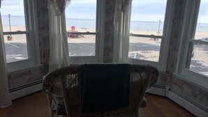 Ein Zimmer mit Korbmöbeln, Blick auf den Strand und einem Parkplatz.