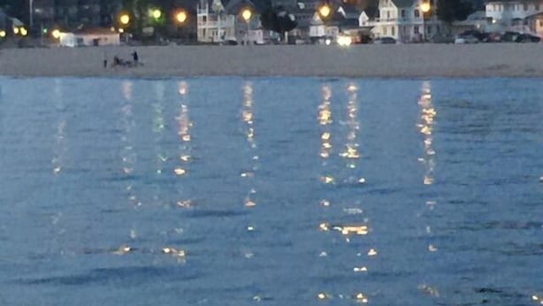 Ein Strand mit Häusern im Hintergrund und Spiegelungen im Wasser.