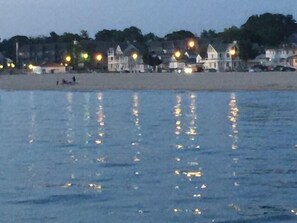 Une plage avec des maisons en arrière-plan et des reflets sur l’eau.
