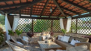 An outdoor covered patio with wicker furniture, stone flooring, and a view through a lattice fence. - Villa Danica with private pool and WIFI Near Center Of The Town And 2km Beach (Pula)