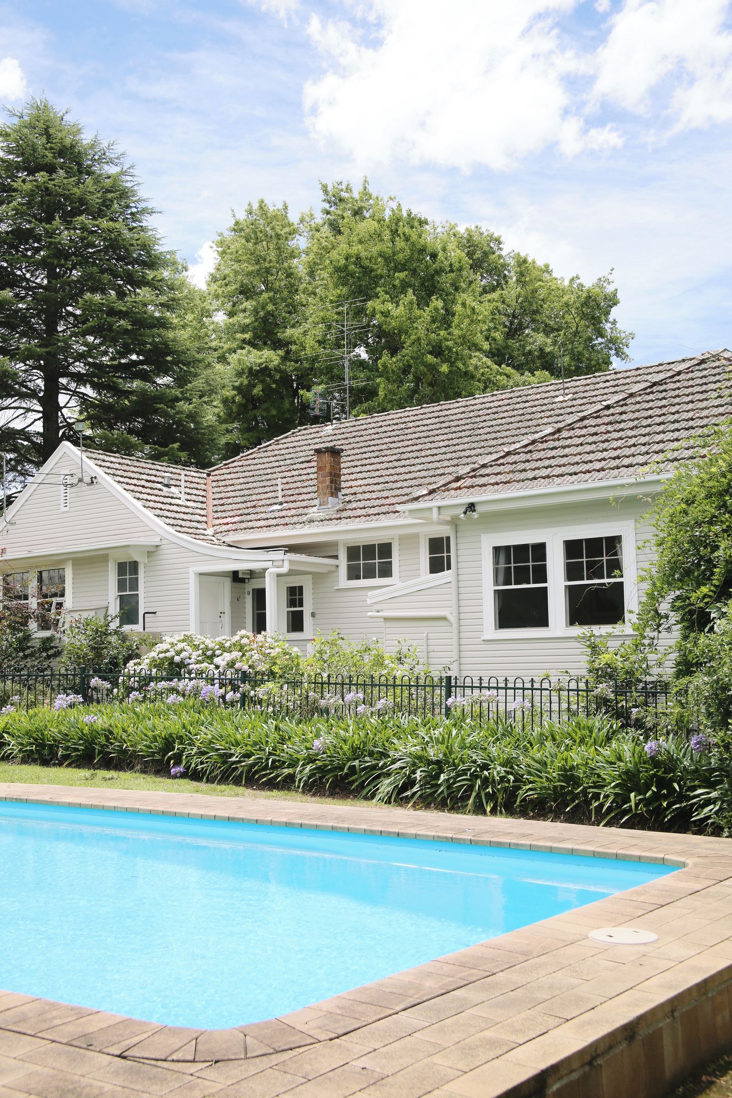 A two-story house with a swimming pool in front.