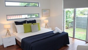 Ein Schlafzimmer mit einem Bett, zwei Nachttischen, einem Fenster und Blick ins Freie.