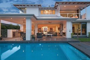 A modern two-story house with a swimming pool, outdoor seating area, and a balcony. - Room for everyone in this luxurious waterfront home! (Gold Coast)