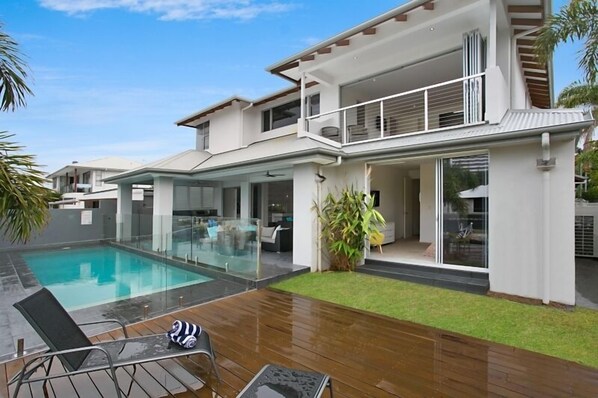 A modern two-story house with a swimming pool, a covered patio, and a well-maintained lawn. - Room for everyone in this luxurious waterfront home! (Gold Coast)
