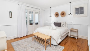 A bedroom with a bed, bedside table, bench, and a small table with a lamp. - Hamptons Escape - Magnificent views (Gerroa)