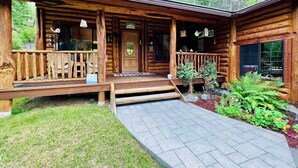A rustic log cabin with a porch, wooden steps, and a small garden area. - Montana Escape Cabin in the woods (Bigfork)