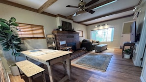A spacious living room with a fireplace, wooden flooring, and a ceiling fan.