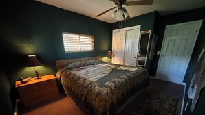 A bedroom with a bed, nightstand, lamp, window, and a door.