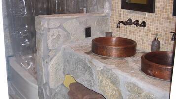 A bathroom with a stone sink, a mirror, and a shower curtain.