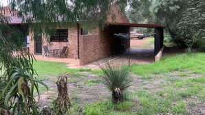 Una casa con un patio, una hamaca y un coche estacionado afuera.