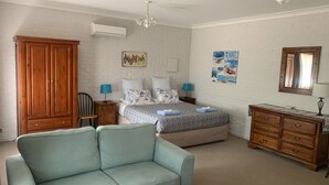 Un dormitorio con una cama, un armario de madera, un sofá azul, un aparador de madera y un ventilador de techo.