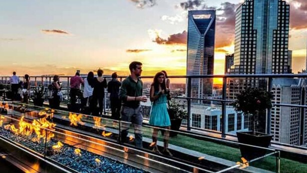 A rooftop terrace with a fire feature, overlooking a cityscape at sunset. - Centrally located in Uptown Charlotte.  Gym, Pool and Free Parking.  Walk everywhere! (Charlotte)
