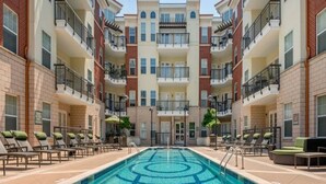 A multi-story hotel with a central swimming pool, balconies on each floor, and outdoor seating areas. - Centrally located in Uptown Charlotte.  Gym, Pool and Free Parking.  Walk everywhere! (Charlotte)