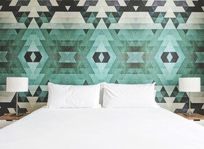 A bed with white linens, two bedside lamps, and a geometric patterned wall behind. - Uptown Charlotte Pool View - 24/7 Fitness Center (Charlotte)