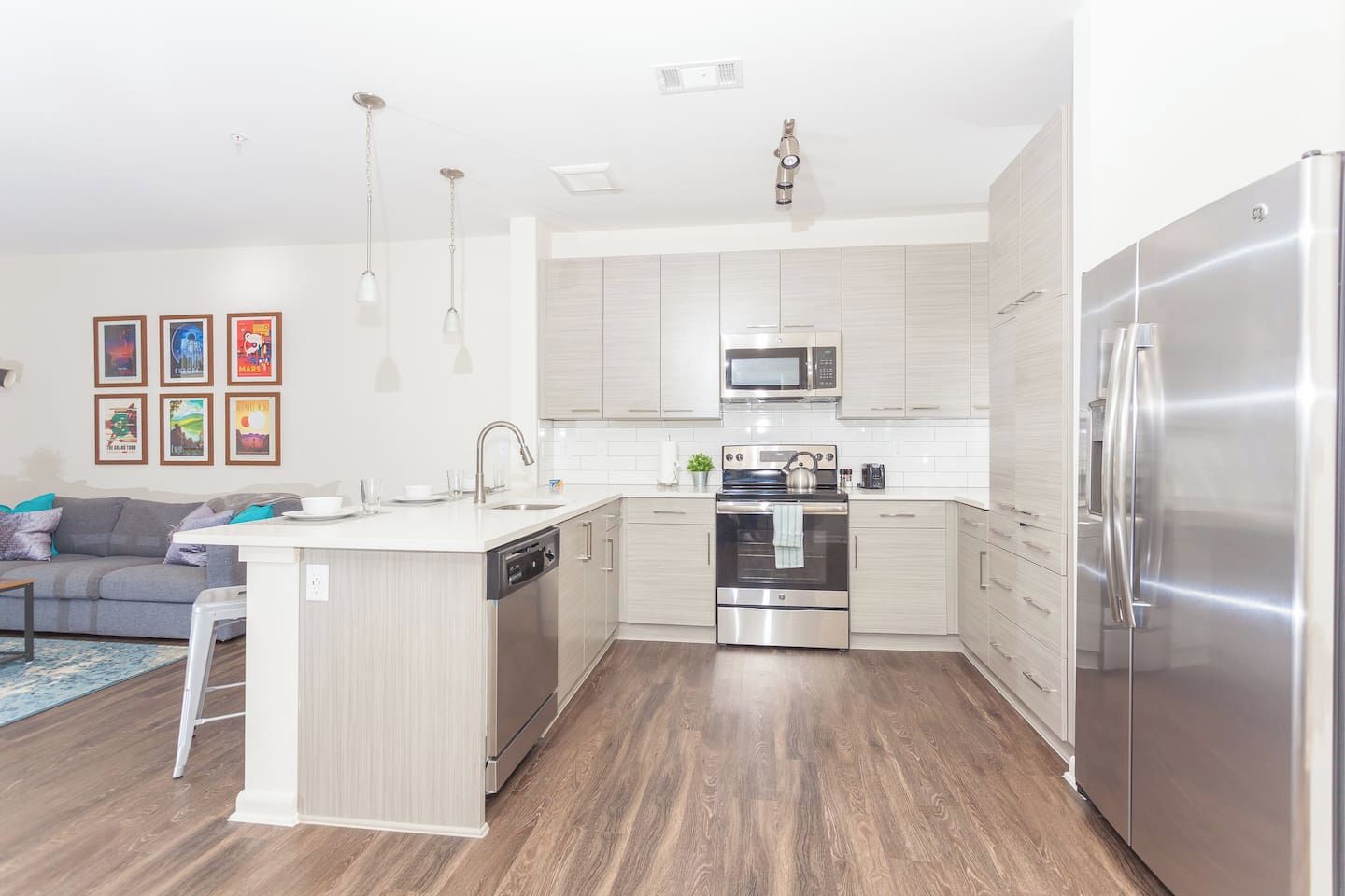 A modern kitchen with a central island, stainless steel appliances, and light-colored cabinetry.