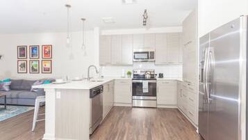 A modern kitchen with a central island, stainless steel appliances, and light-colored cabinetry.