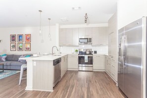 A modern kitchen with a central island, stainless steel appliances, and light-colored cabinetry. - Uptown Charlotte Pool View - 24/7 Fitness Center (Charlotte)