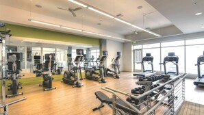 A gym with various exercise equipment, large windows, and a green accent wall. - Centrally located in Uptown Charlotte.  Gym, Pool and Free Parking.  Walk everywhere! (Charlotte)