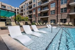 A swimming pool with lounge chairs and a stone building in the background. - Uptown Charlotte Pool View - 24/7 Fitness Center (Charlotte)