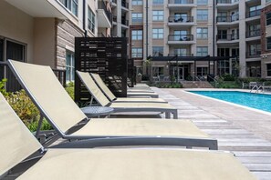 A poolside area with sun loungers and a pool. - Uptown Charlotte Pool View - 24/7 Fitness Center (Charlotte)