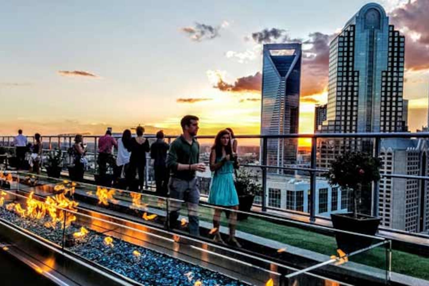 A rooftop terrace with a fire feature, overlooking a cityscape with modern buildings.