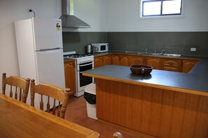 Une cuisine équipée d’un réfrigérateur, d’une cuisinière, d’un four à micro-ondes et de meubles de rangement en bois.
