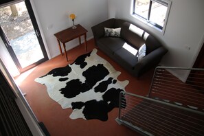 Un salon avec un canapé, une table basse, un tapis en peau de vache et un escalier.