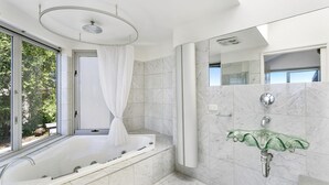 A modern bathroom with a freestanding bathtub, a glass shower enclosure, and a marble-tiled shower area. - The Cliff's Edge (Fairhaven)