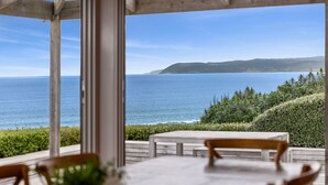 A covered outdoor seating area with a view of the sea and hills. - The Cliff's Edge (Fairhaven)