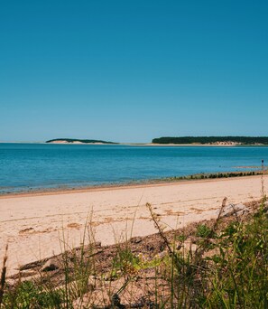 A beach with clear blue water, sandy shore, and distant islands.
