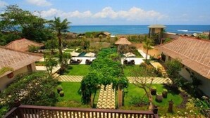 Ein Resort mit strohgedeckten Hütten, einem zentralen Innenhof und Blick auf den Ozean.