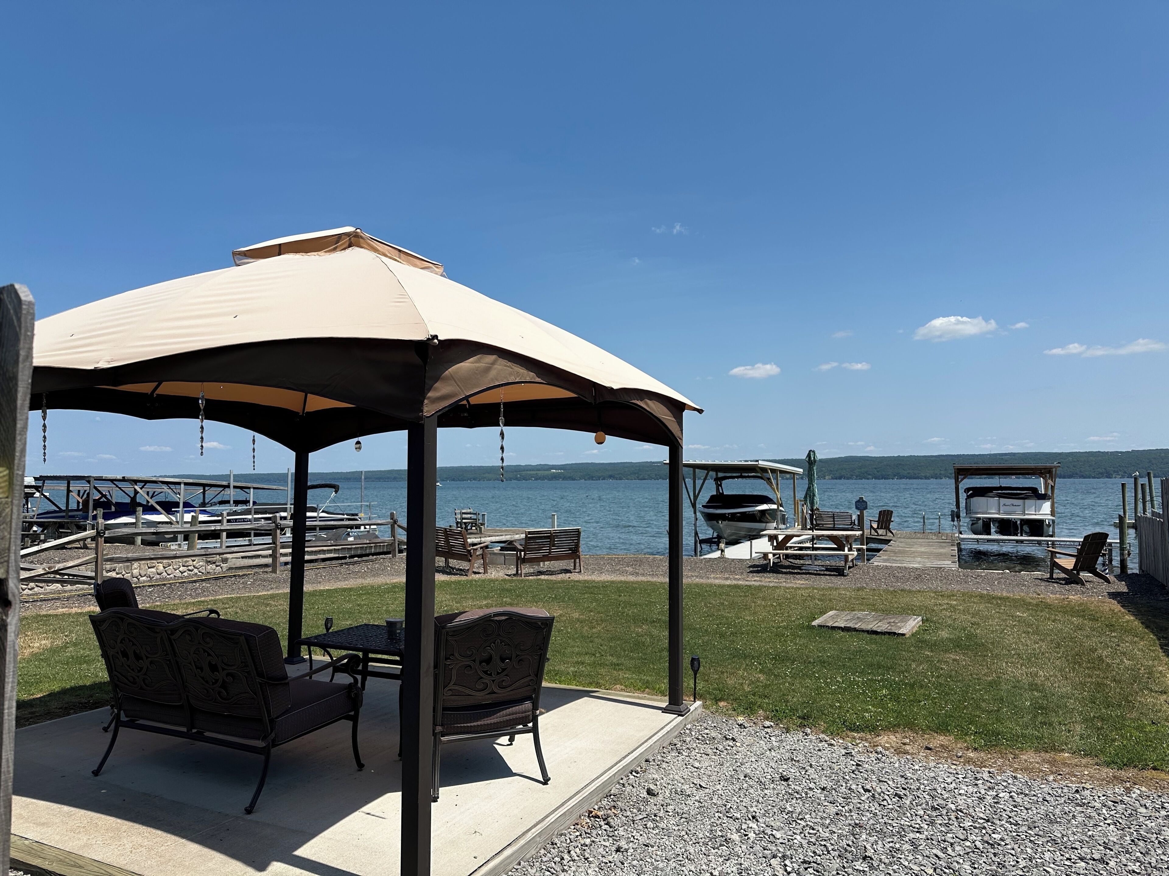 Ein Pavillon mit Blick auf einen See, Sitzgelegenheiten im Freien und ein Steg mit Booten.