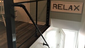 Una escala amb barana de metall negre, un senyal amb la paraula 'RELAX' a dalt i una porta blanca a la base.