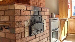 Eine Küche mit Kamin aus Backstein, Holzschränken und integriertem Backofen.
