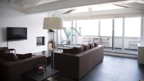 Ett modernt vardagsrum med en stor soffa, en platt-TV och en golvlampa.