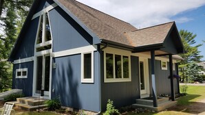 Een modern huis met twee verdiepingen, een donkerblauwe gevel, witte sierlijsten en een schuin dak.