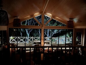A cozy interior with a wooden ceiling, large windows, and a view of an outdoor deck. - Beautiful Beachfront Palm Beach Style House (Rosedale)
