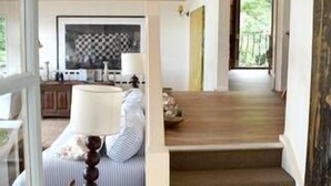 A staircase leading to a second floor with a wooden finish, a dining area with a checkered tablecloth, and a lamp on a side table. - Beautiful Beachfront Palm Beach Style House (Rosedale)