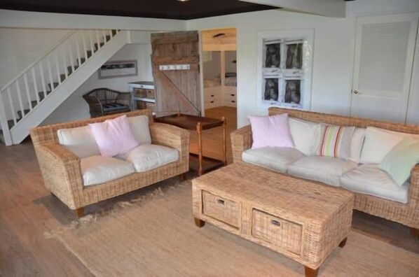 A room with two wicker sofas, a small wooden coffee table, and a staircase leading to another level. - Beautiful Beachfront Palm Beach Style House (Rosedale)