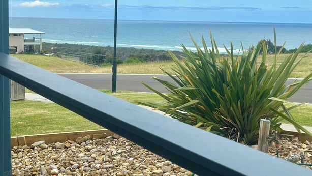 A balcony with a view of the ocean, a street lamp, and a plant. - Large spacious house with many ocean views. Set in a peaceful quiet location. (Lake Bunga)
