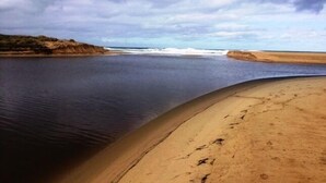 A beach with a curved shoreline, calm water, and a cloudy sky. - Large spacious house with many ocean views. Set in a peaceful quiet location. (Lake Bunga)