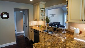 A kitchen with granite countertops, a sink, and a dining area with a black leather couch. - Lakefront Oasis Centrally Located. Elegant, spacious and you're going to love it (Virginia Beach)