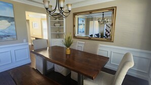 A dining room with a wooden table, beige chairs, a chandelier, and a large mirror on the wall. - Lakefront Oasis Centrally Located. Elegant, spacious and you're going to love it (Virginia Beach)