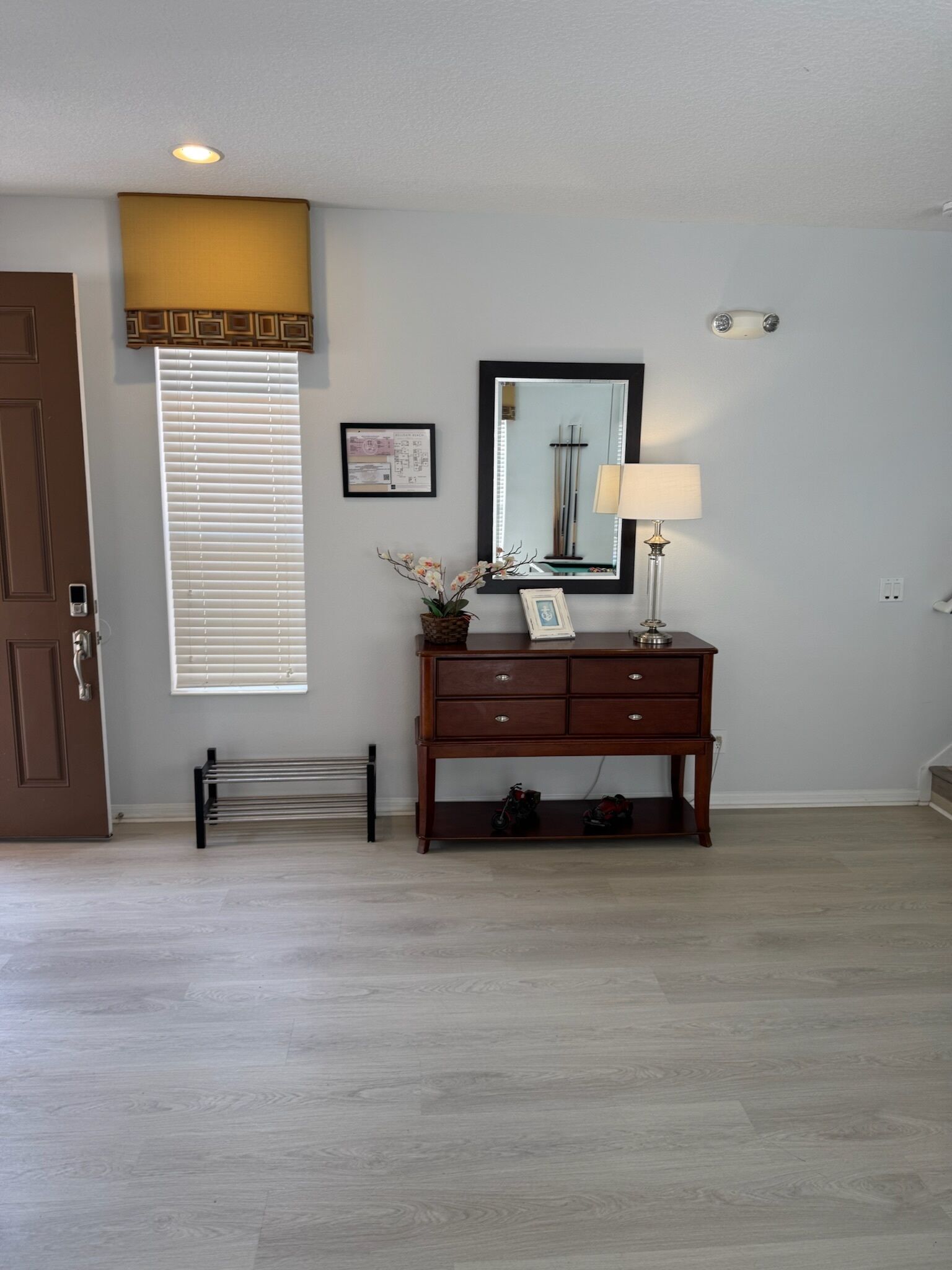 A room with a wooden dresser, a mirror, a radiator, and a door.