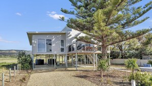 A two-story house with a covered porch, a staircase leading to an upper level, and a view of the surrounding landscape. - Sea View at Silver Sands - Sitting Pretty with Sea, Hills and Washpool Views (Aldinga Beach)