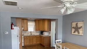 A kitchen with wooden cabinets, a white refrigerator, a microwave, and a dining table with chairs.
